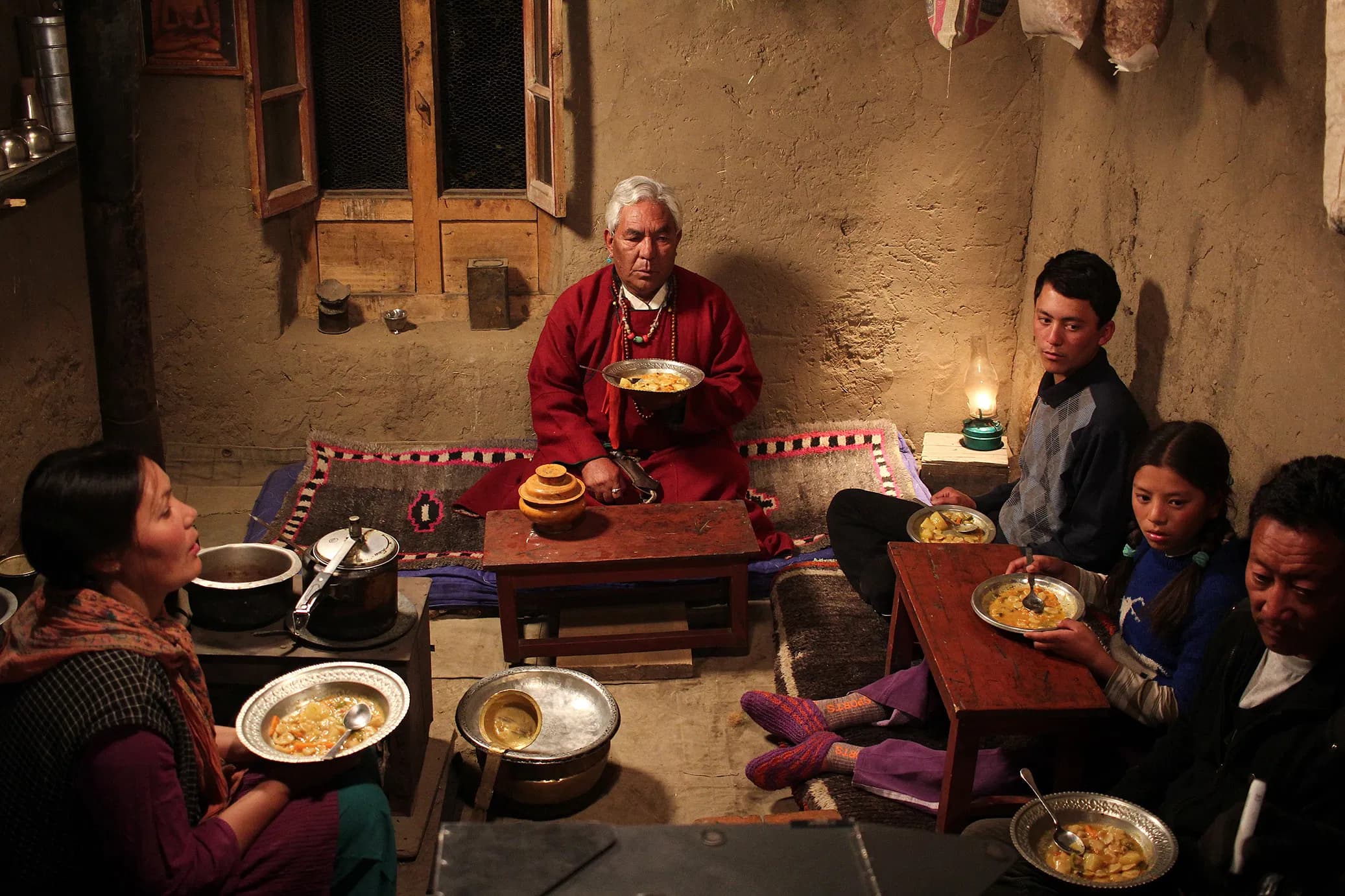 Chuskit and her family gathered in a warm traditional Ladakhi kitchen sharing a dinner meal around the hearth with her grandfather