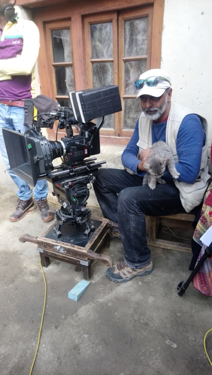 Cinematographer Arvind Kannabiran taking a gentle break holding a grey kitten beside the RED camera rig on set