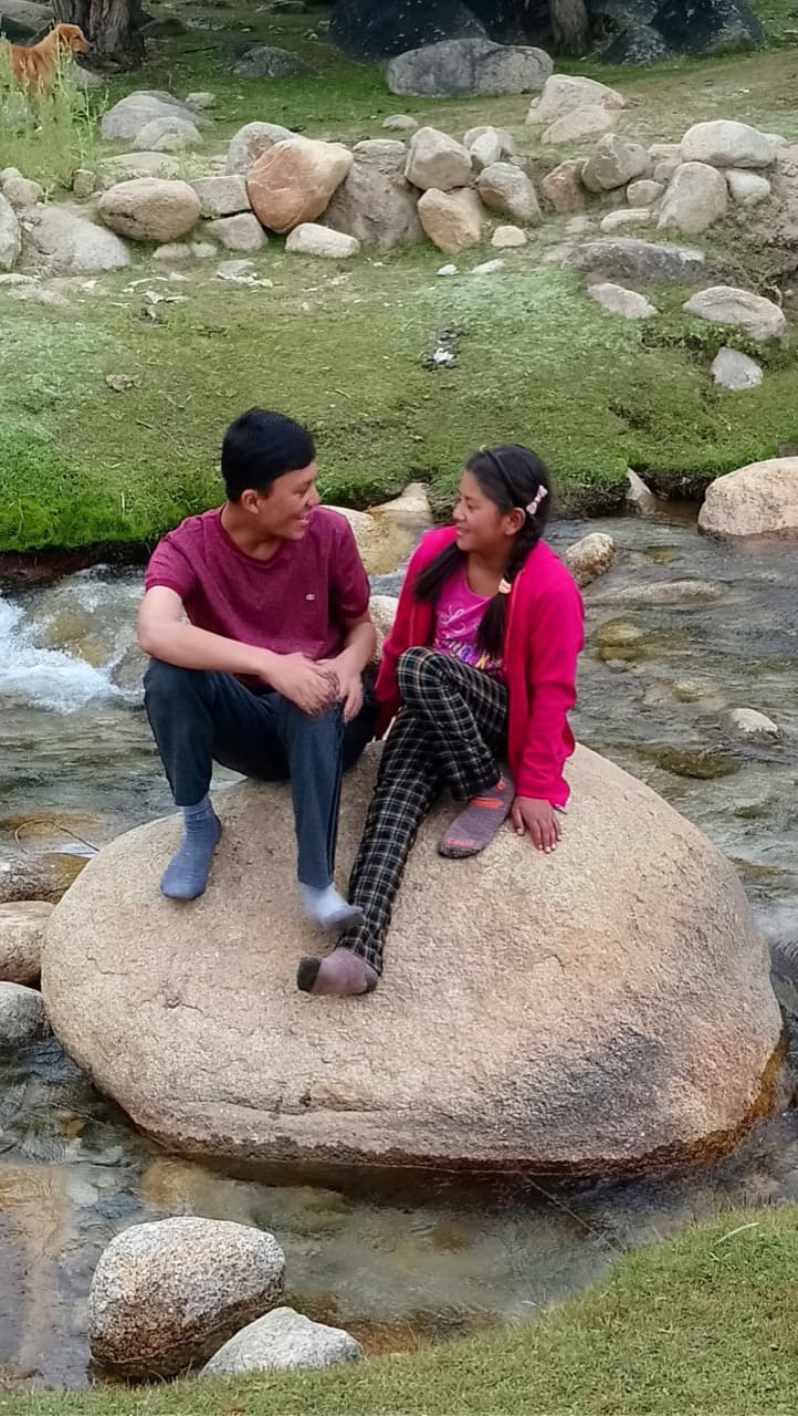 Chuskit and her brother Stanzin sitting together on a river boulder having a heartfelt conversation in Ladakh